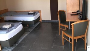 Ein kleiner, moderner Raum mit einem Bett, einem Schreibtisch und einem Stuhl.