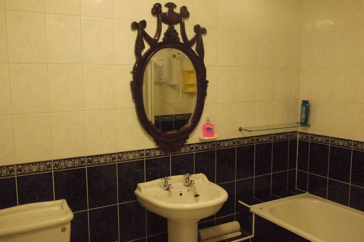 Une salle de bain avec un lavabo blanc, un miroir, une baignoire et des murs carrelés en noir et blanc.