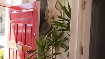 A red door with a brass handle and a small plant beside it.
