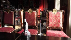 A bar area with red upholstered chairs, a bottle on the table, and a menu on the wall. - 7 Houses (Armagh)