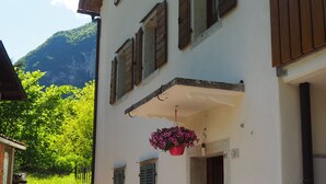 A building with a stone-paved entrance, wooden shutters, and potted plants. - KALIPE' DOLOMITI Appartment (LONGARONE (BL))