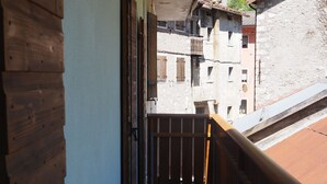 A narrow corridor with wooden walls and a tiled floor, leading to a balcony with a wooden railing. - KALIPE' DOLOMITI Appartment (LONGARONE (BL))