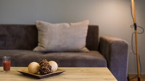 Una sala de estar moderna con un sofá, una mesa con una copa de bebida roja y elementos decorativos.