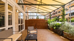 Un patio cubierto con mobiliario exterior, cerca de madera y plantas en macetas.
