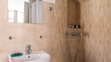 Un baño con lavabo, espejo, ducha y paredes con azulejos.