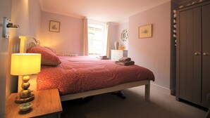 A bedroom with a bed, bedside table, lamp, and a wardrobe. - 2 Bedroom City Centre Cottage set in a Private Courtyard (Canterbury)