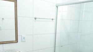 Un bany amb una cabina de dutxa de vidre, un lavabo amb taulell de marbre i un vàter.