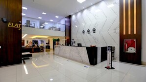 Un moderno vestíbulo de hotel con un mostrador de recepción de mármol, un balcón en el segundo piso y un suelo de baldosas impecable.