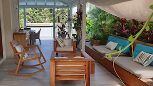 Une vaste terrasse avec des meubles en bois, un canapé avec des coussins et des plantes en pot.