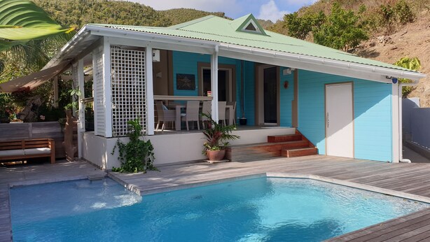 Une maison avec une piscine, un patio couvert et une vue sur les collines.