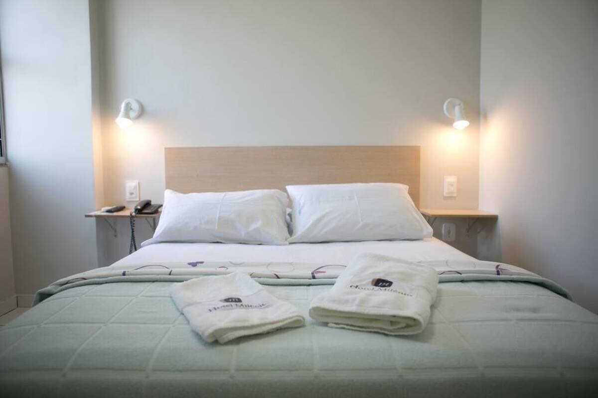 Ein ordentlich bezogenes Bett mit weißen Leinen, zwei Kissen und zwei gefalteten Handtüchern.