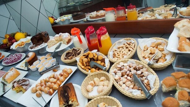 Una mesa de buffet con diversos alimentos, como pasteles, pan y bebidas.