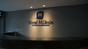 Un mostrador de recepción con un letrero que indica Hotel Milênio.