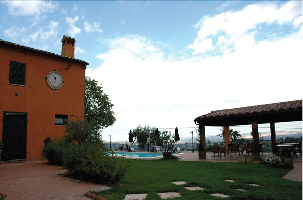 Un edificio con un reloj, piscina y zona de estar al aire libre.