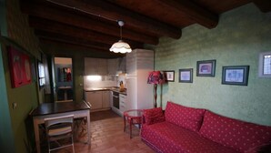 A compact living space with a kitchenette, a dining table, and a red sofa. - Poggio Montali (Monte Roberto)