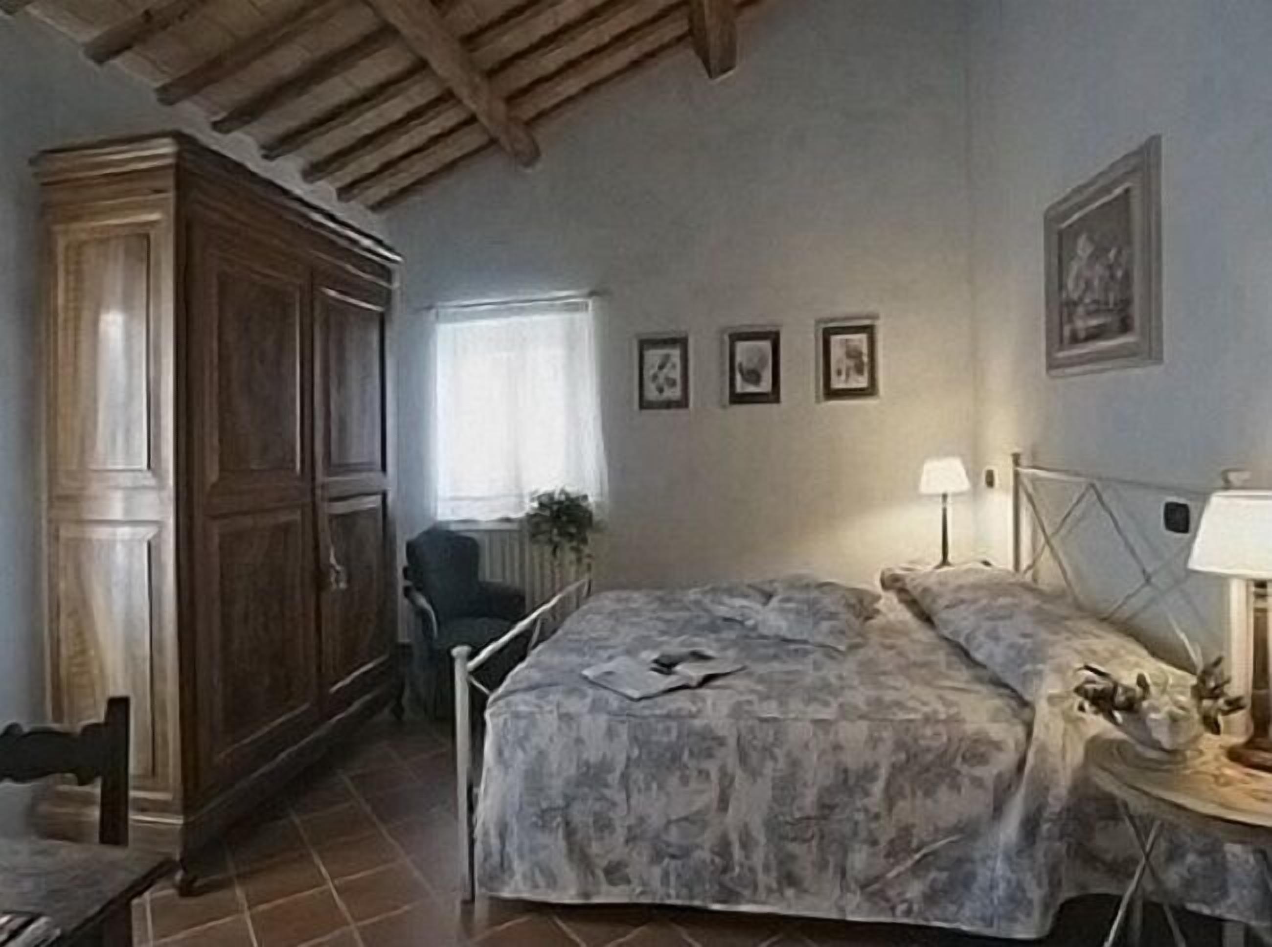 Un dormitorio con cama, una silla, un escritorio y un armario.