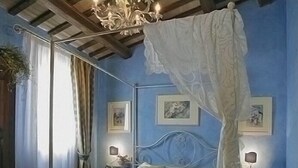A bedroom with a four-poster bed, a chandelier, and framed artwork on the walls. - Poggio Montali (Monte Roberto)