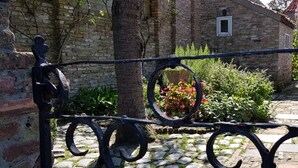 A stone-paved courtyard with a wrought iron fence, a brick wall, and a small window. - Charming house in Westenschouwen (Burgh-Haamstede)