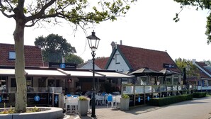 A street with outdoor seating, a pizzeria, and a cafe. - Charming house in Westenschouwen (Burgh-Haamstede)