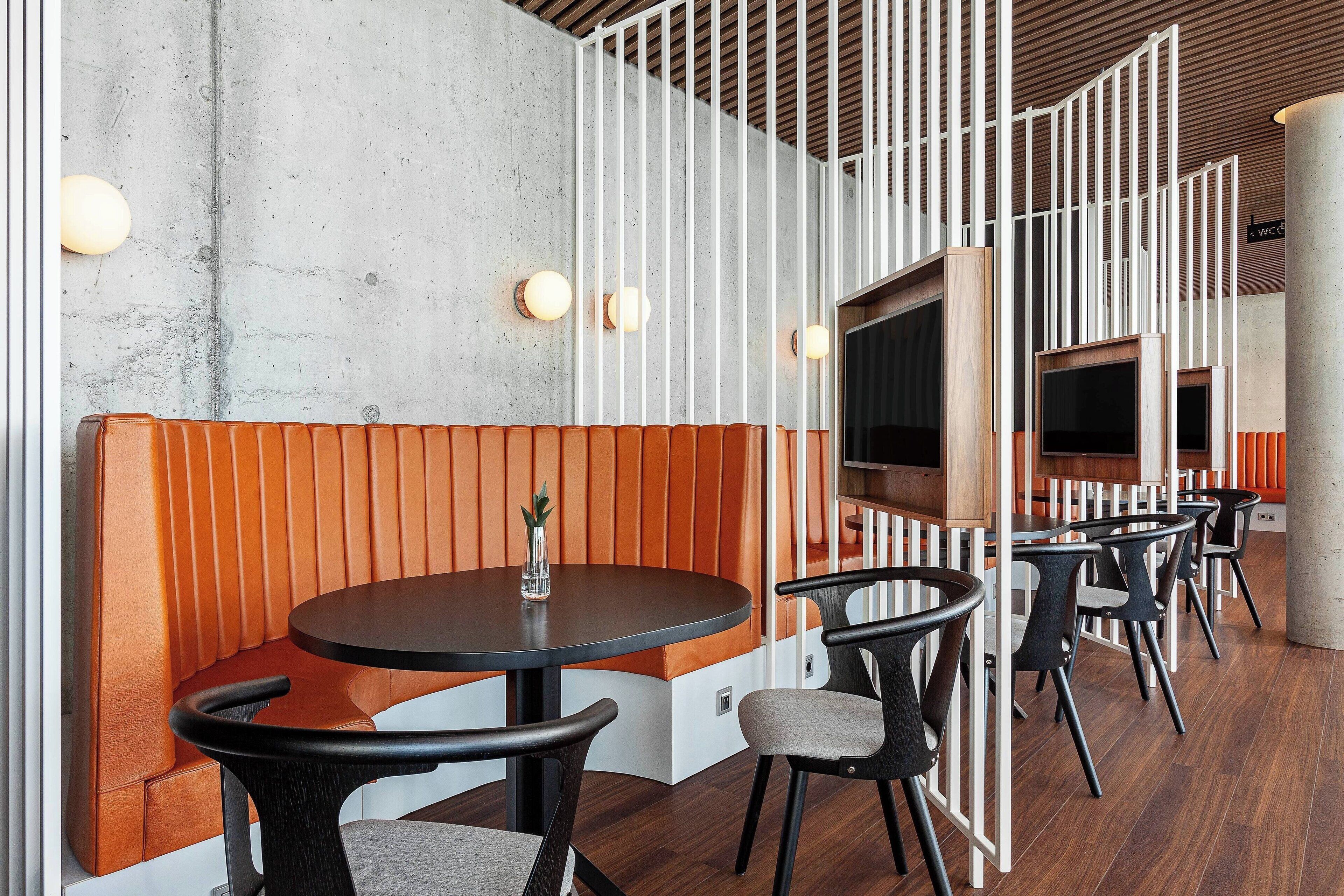 Un interior moderno con una mesa redonda, asientos acolchados y un techo de madera.