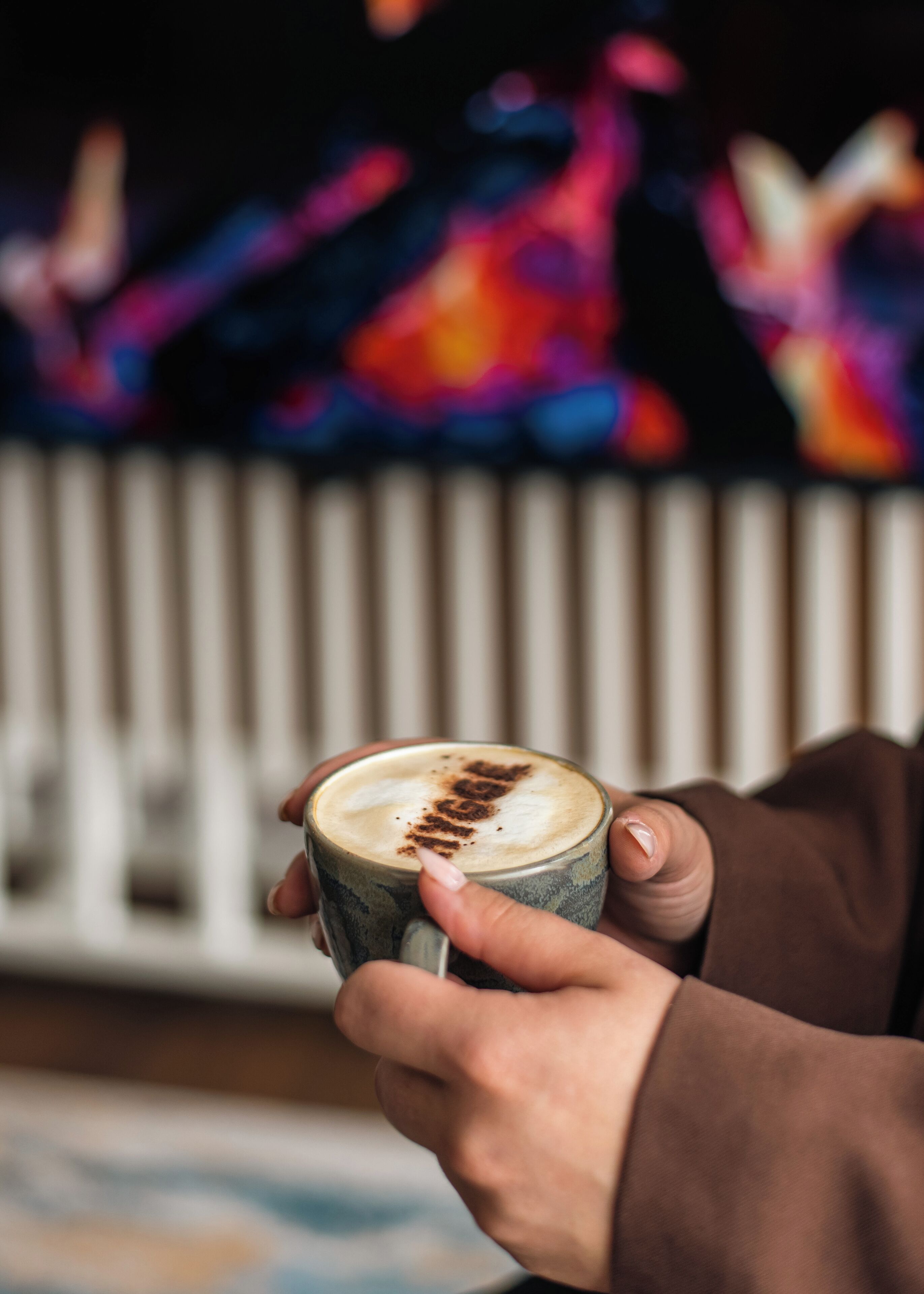 A person holding a cup with a latte art design.