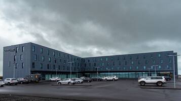 A modern building with a courtyard, multiple parking spaces, and a row of parked cars.