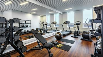 A gym with exercise equipment, weight machines, treadmills, and a bench.