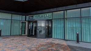 Un edificio moderno con un letrero que dice "COURTYARD BY MARRIOTT" y una entrada de cristal.