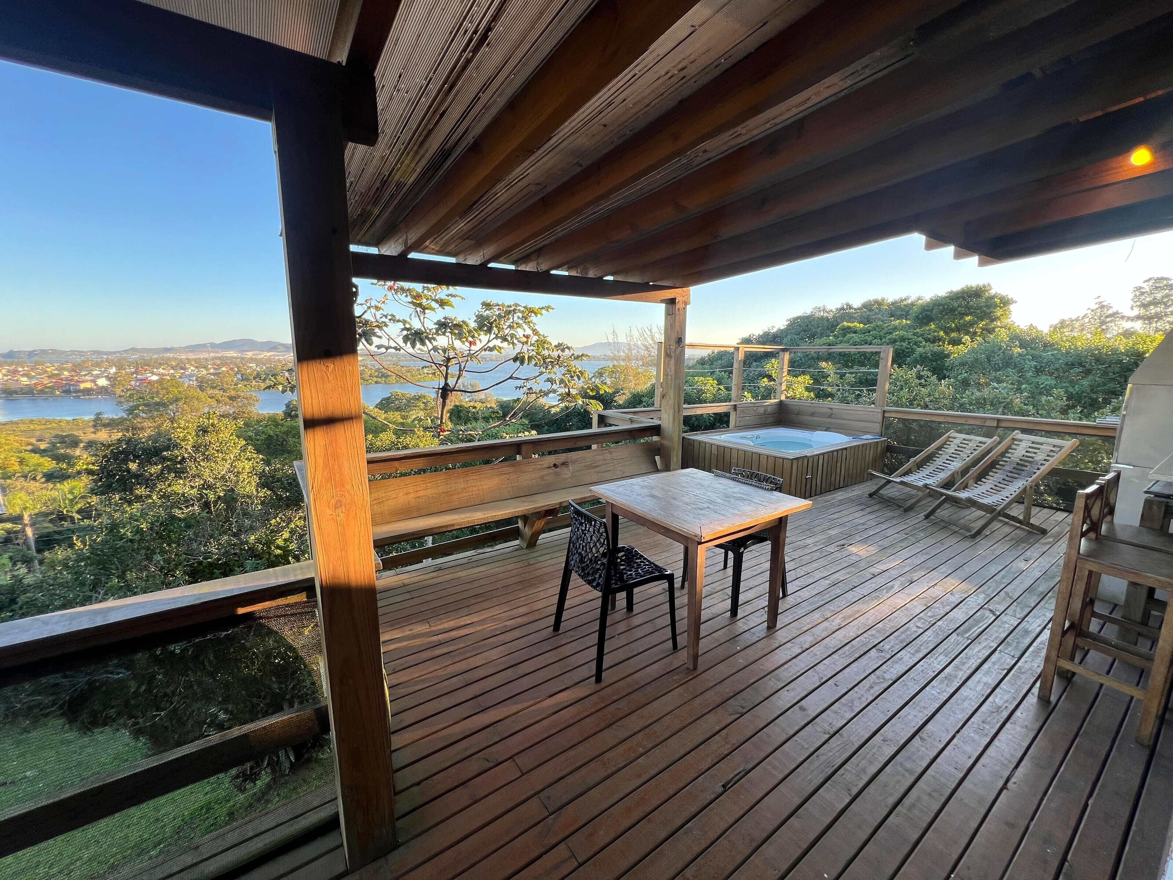 Una terraza de madera con un jacuzzi, sillas de descanso y una mesa con sillas.