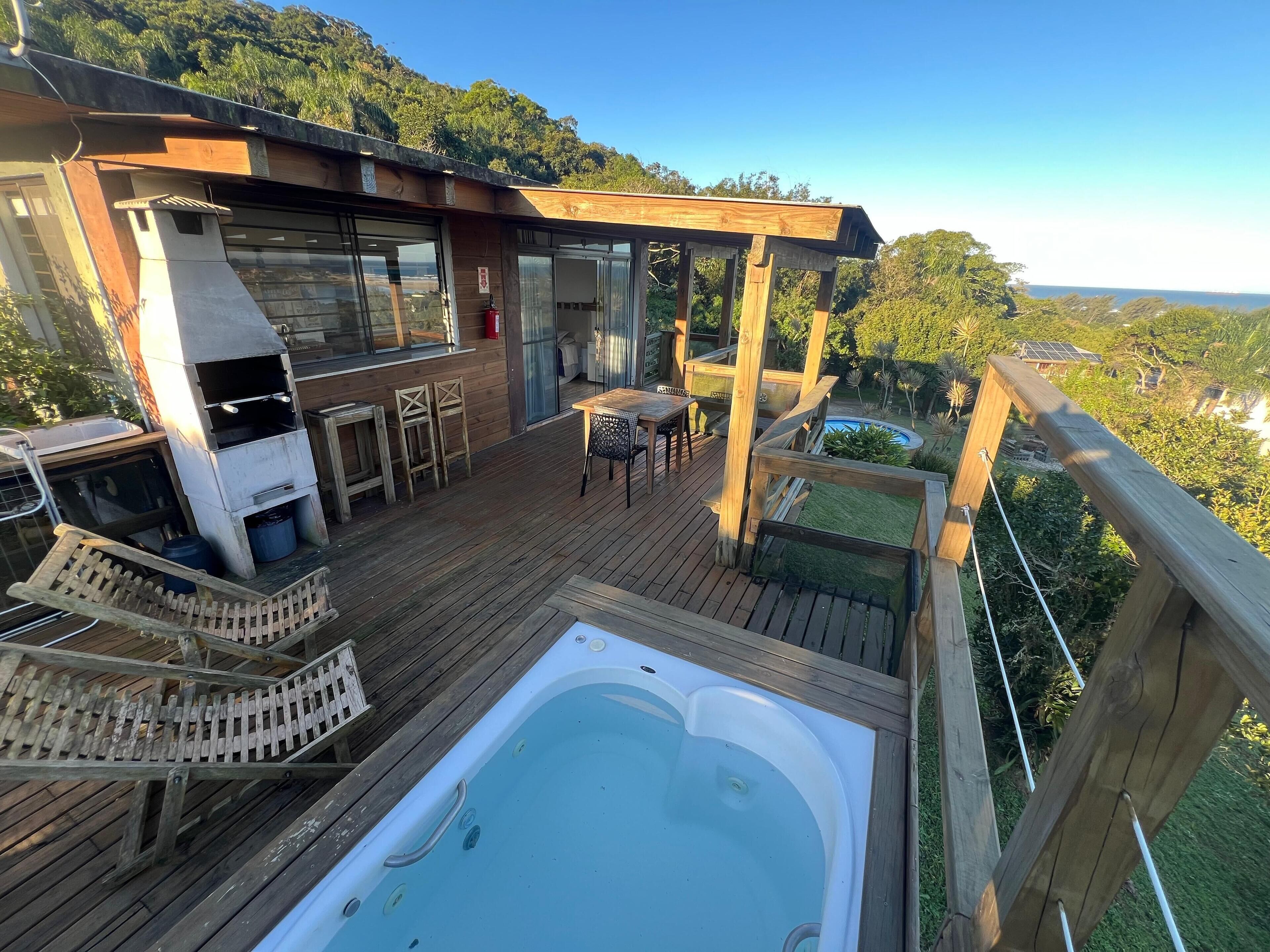 Una terraza de madera con jacuzzi, mobiliario exterior y zona de barbacoa.