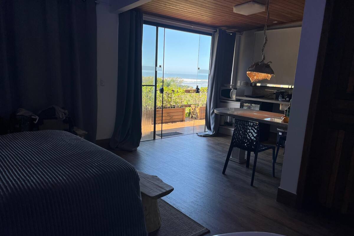 A bedroom with a bed, a desk, and a view of the outdoors.