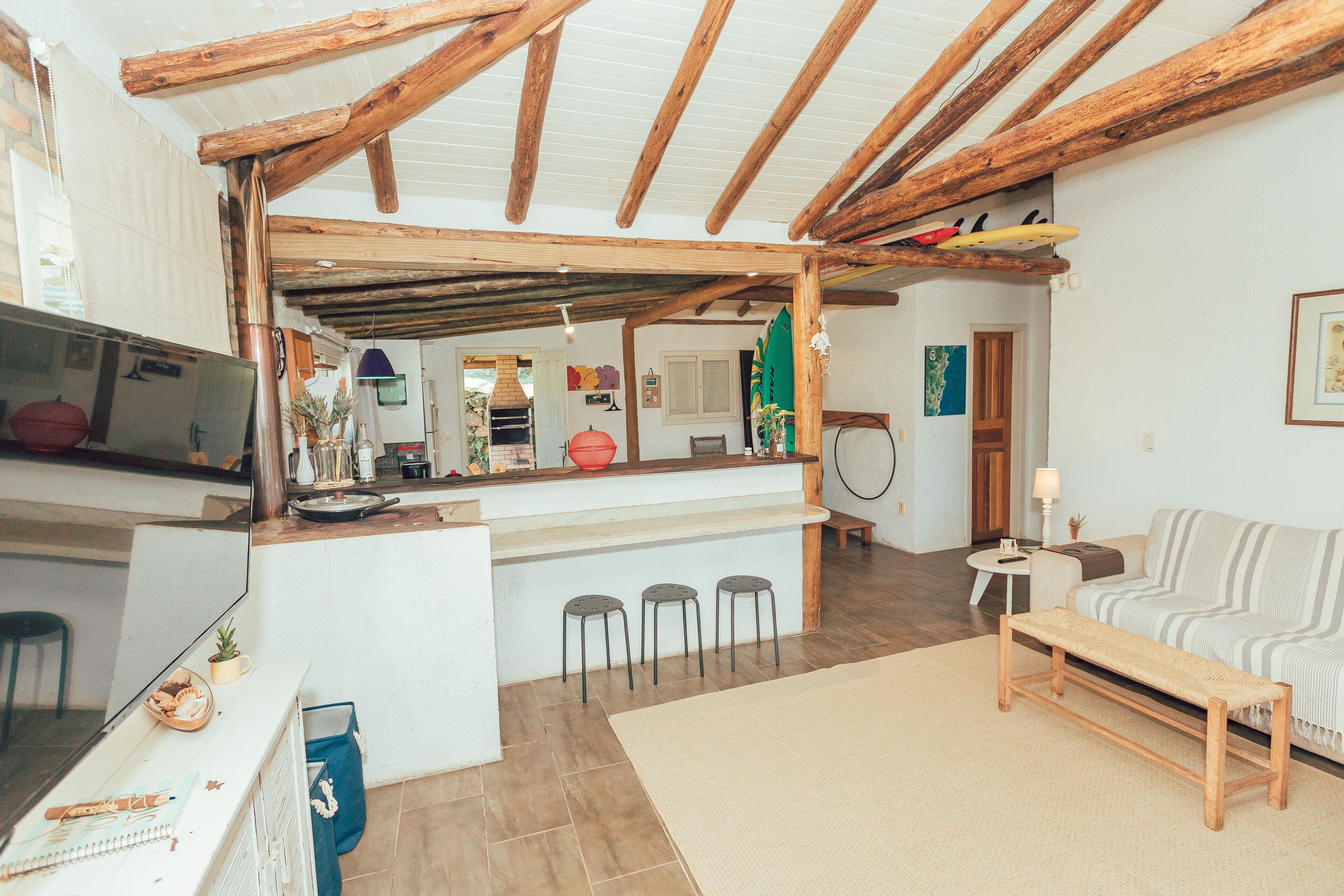 A cozy living area with a wooden ceiling, a kitchen counter, a sofa, and a bench.