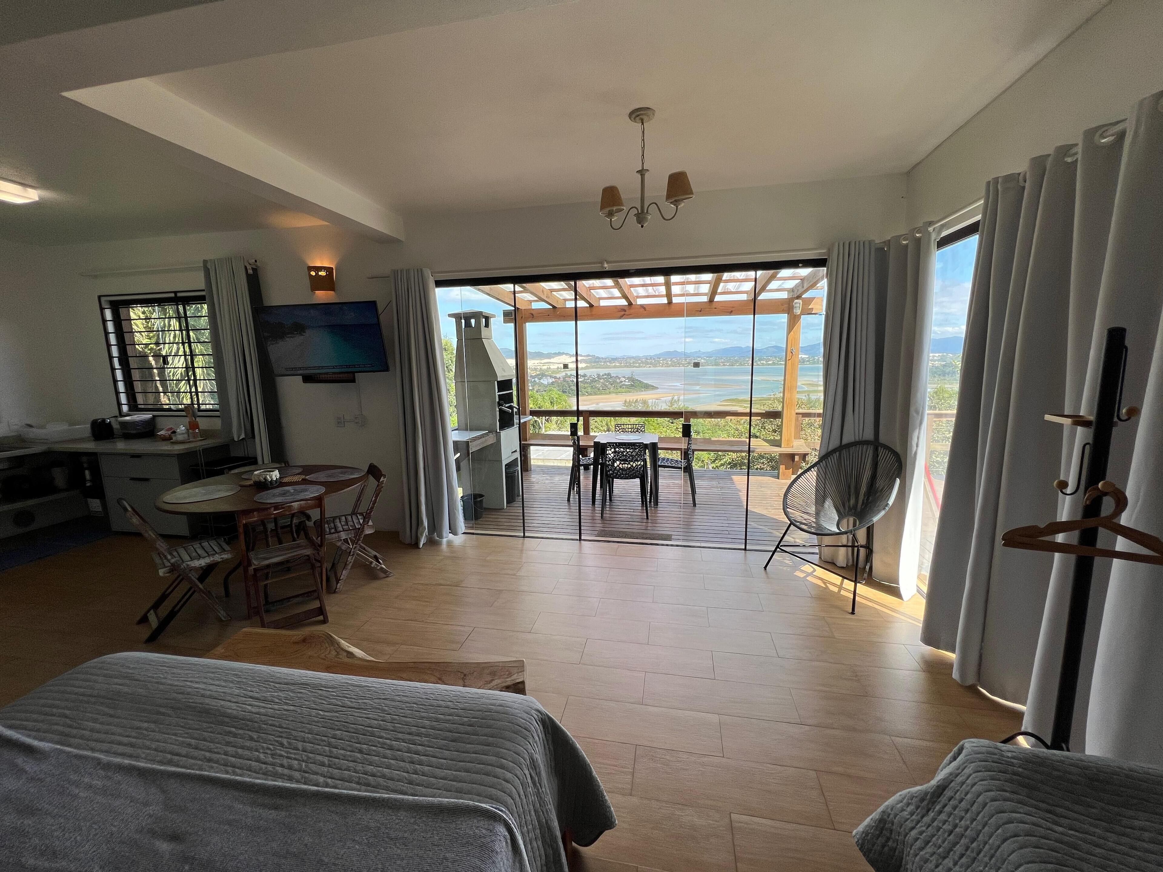 A spacious room with a balcony, a dining area, and a TV.