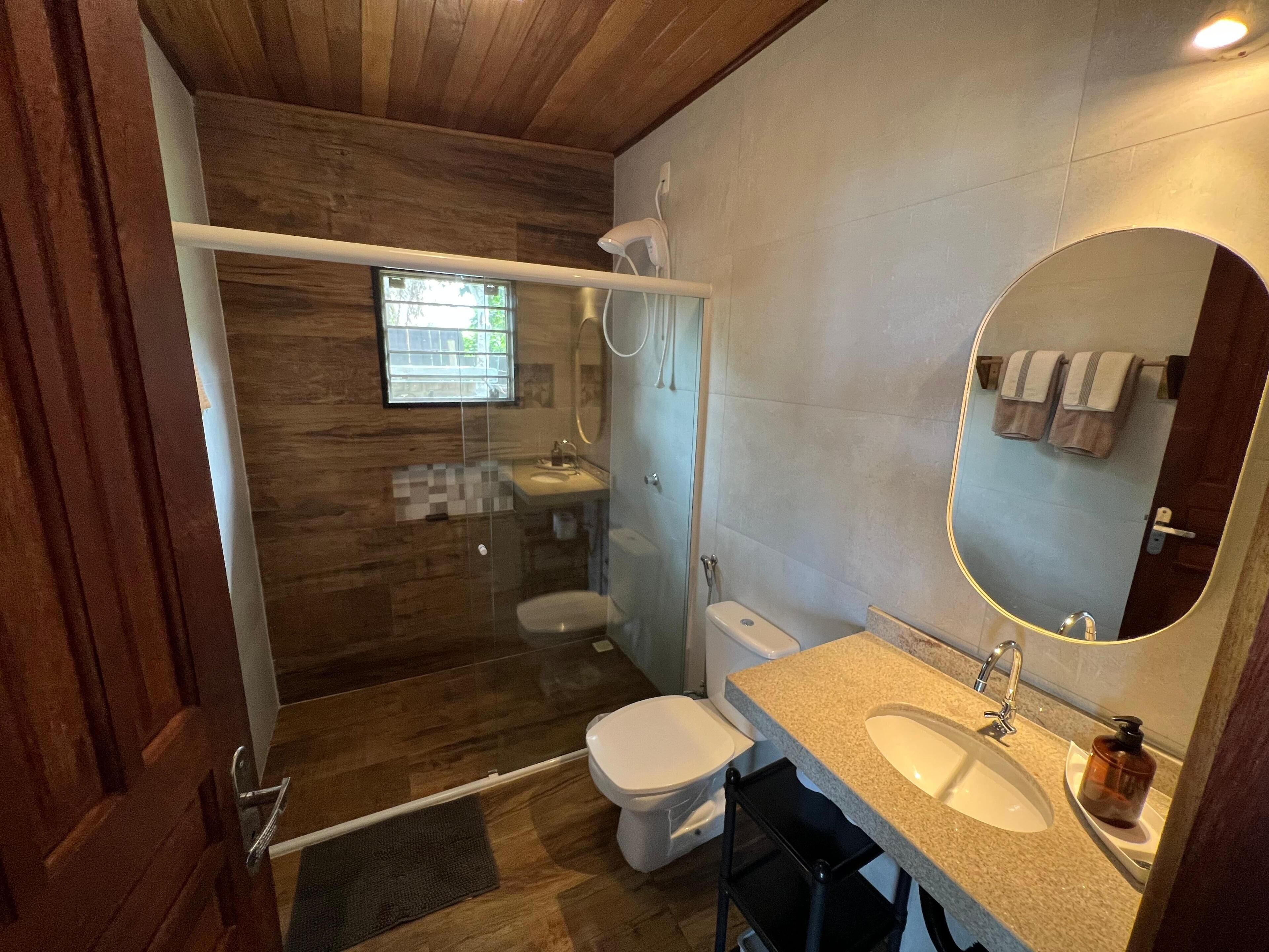 Une salle de bain équipée d’une douche, de toilettes, d’un lavabo et d’un miroir.