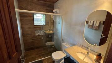 Une salle de bain équipée d’une douche, de toilettes, d’un lavabo et d’un miroir.