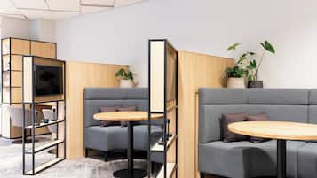 A modern lounge area with grey sofas, wooden tables, and a television.