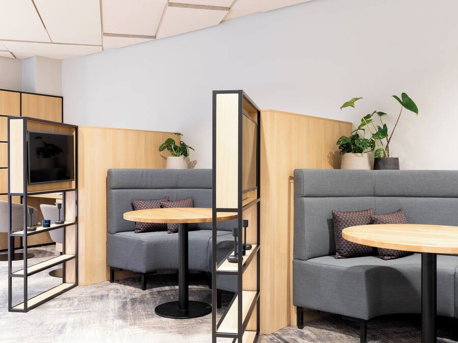 A modern lounge area with grey sofas, wooden tables, and a television.