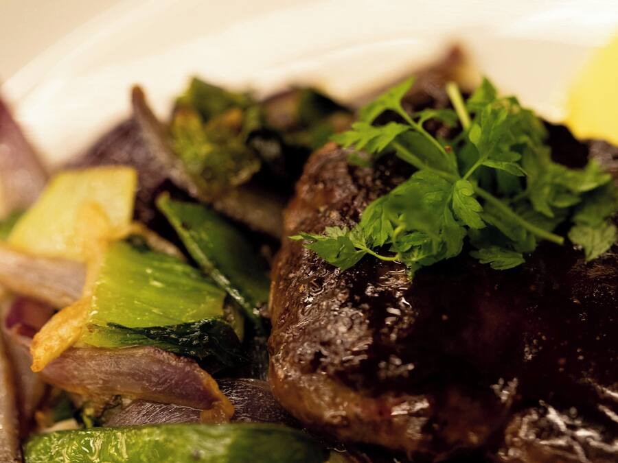 A close-up of a dish with mushrooms, green vegetables, and a garnish.