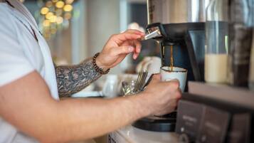 Iemand bedient een koffieapparaat, waarschijnlijk in een café of restaurant.