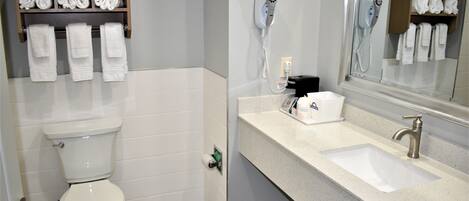 Une salle de bain moderne équipée de toilettes, d’un lavabo, d’un sèche-cheveux et d’un porte-serviettes.