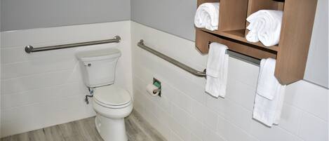 Baño con inodoro, barras de apoyo y toallero.