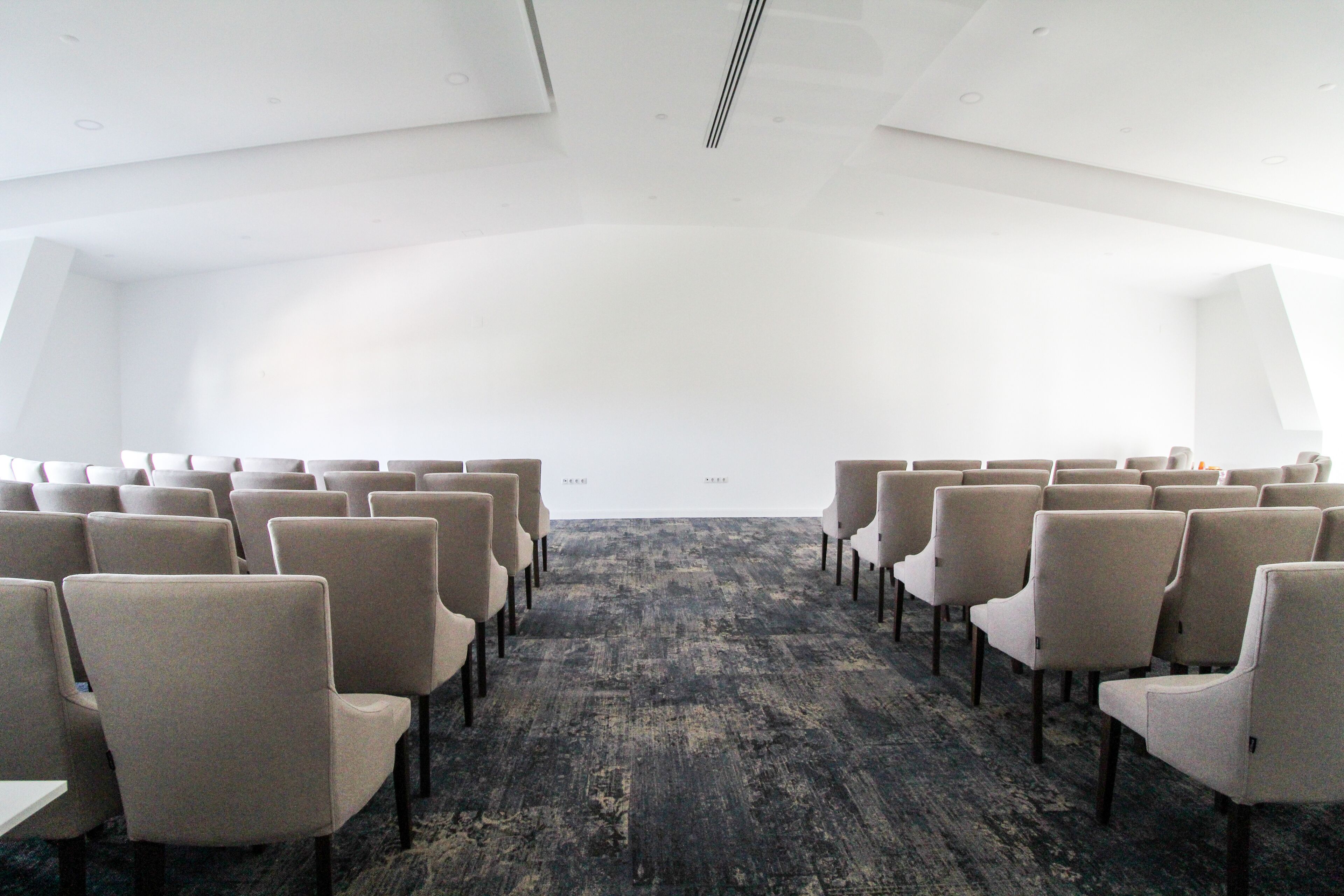 A conference room with rows of chairs facing a white wall.