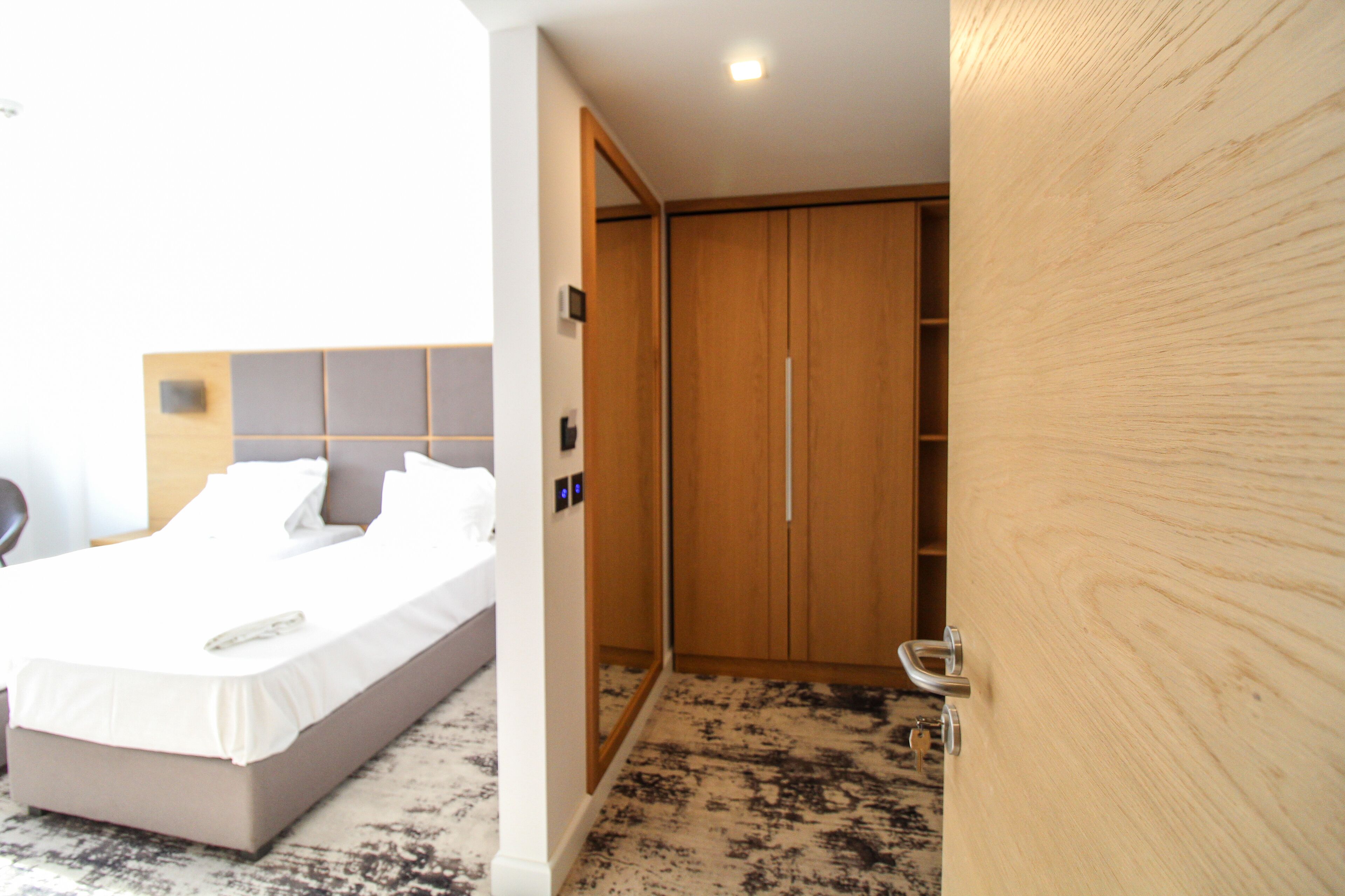Une chambre d’hôtel avec un lit, une armoire en bois et une salle de bain avec douche.