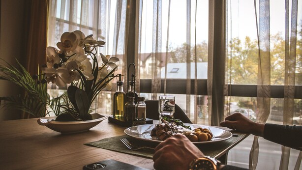 Uma mesa de jantar com um prato de comida, um copo de água e um smartphone.