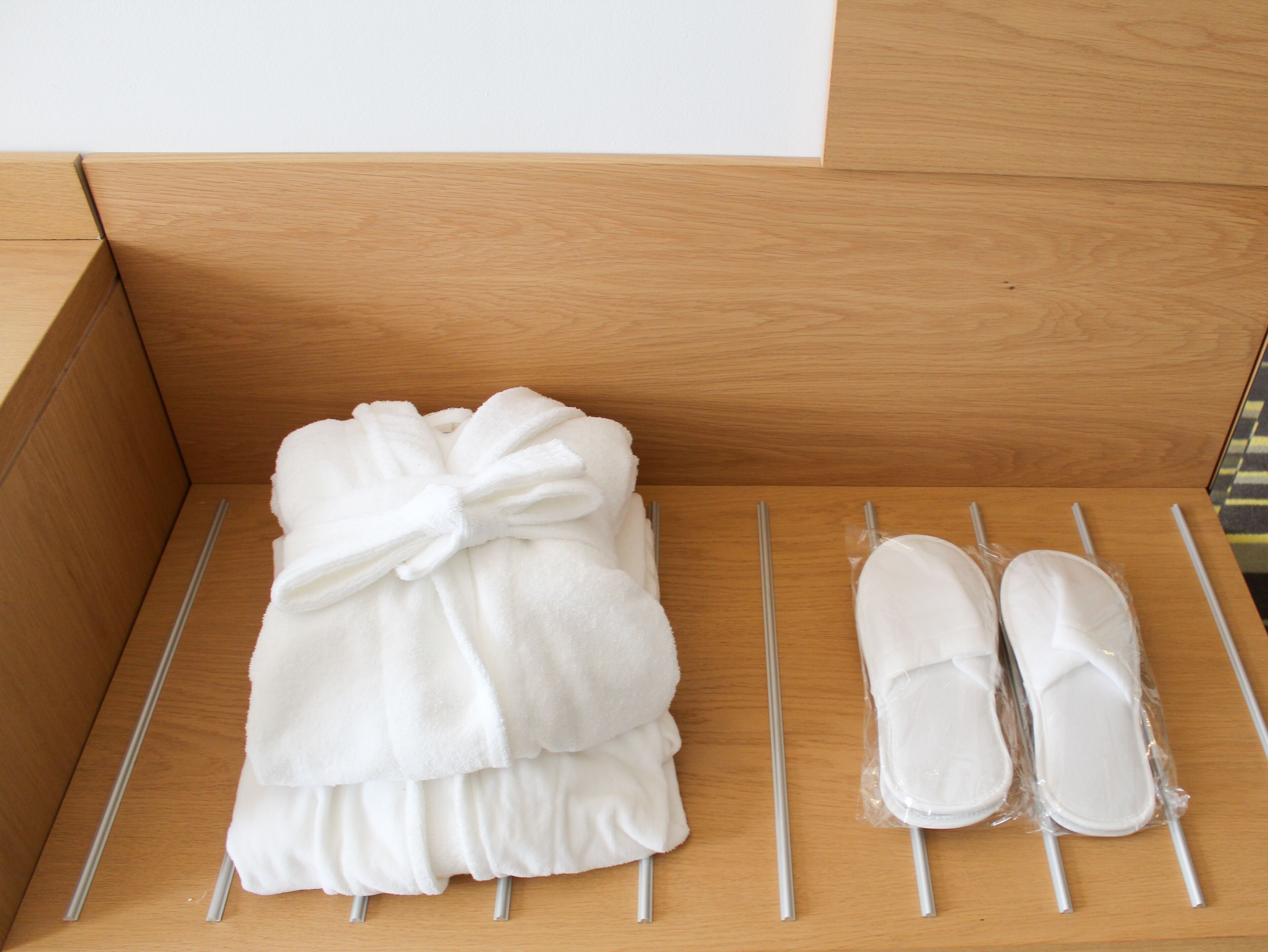 A wooden storage box with a white towel and a pair of white slippers.