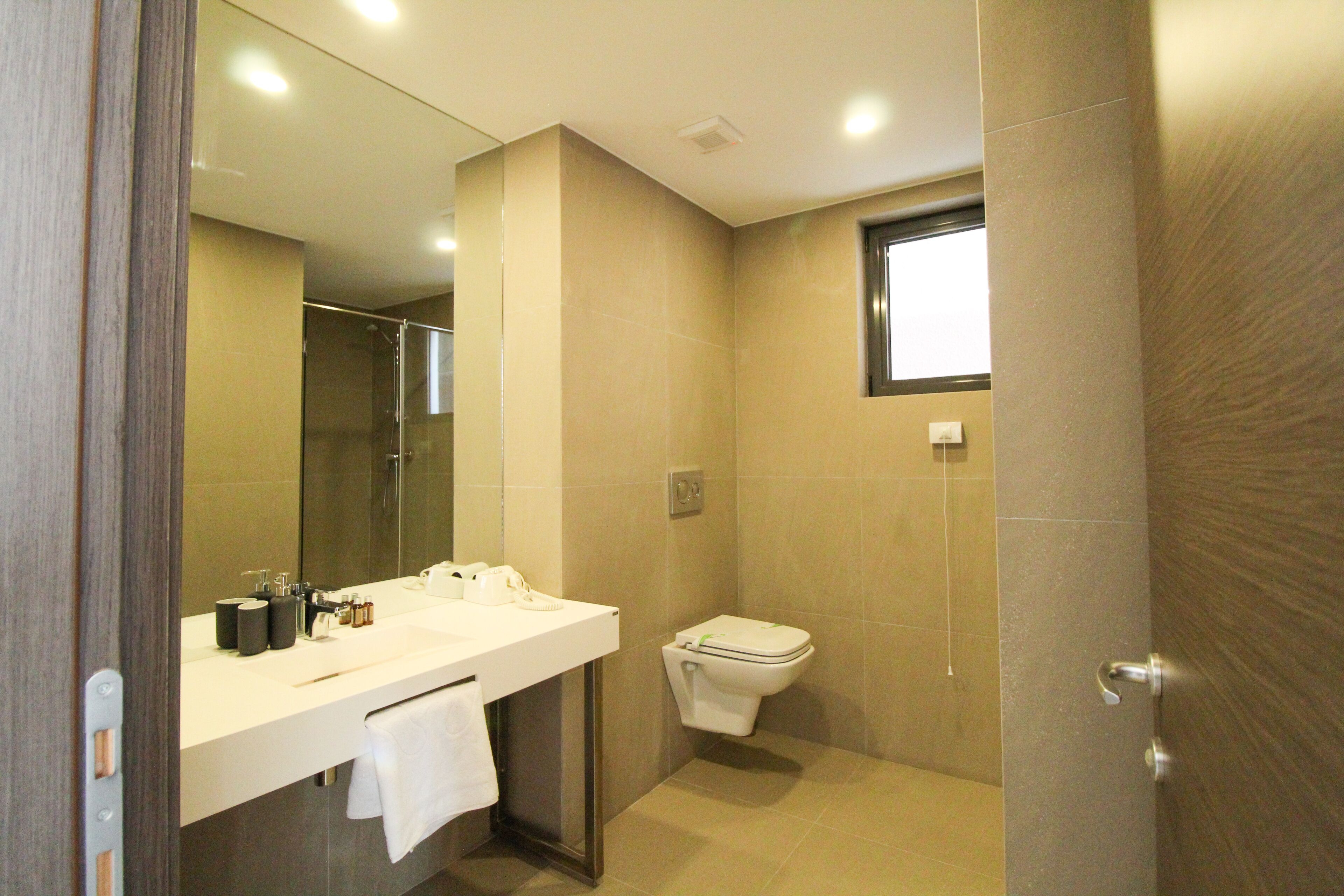 Un bagno moderno con uno specchio grande, un lavandino bianco e un water.