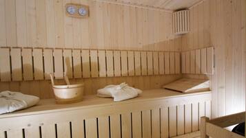 A wooden sauna with benches, a wooden bucket, and towels.