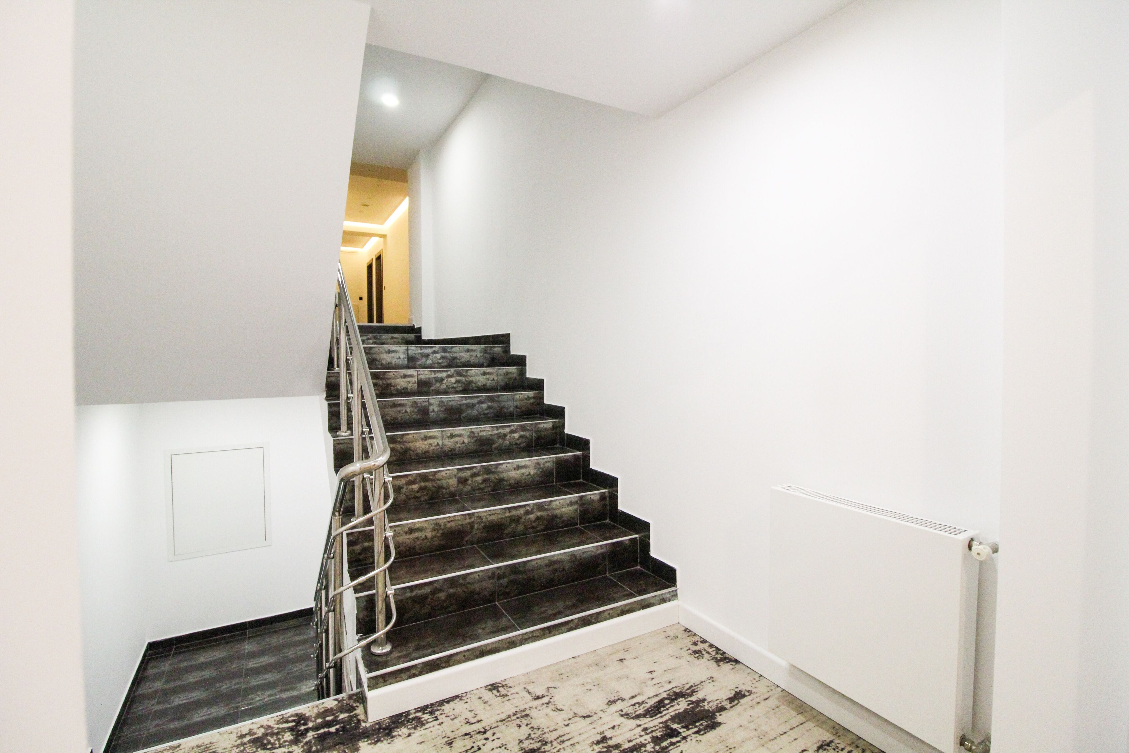 Una escalera con escalones oscuros y una barandilla de metal que lleva a un piso superior.