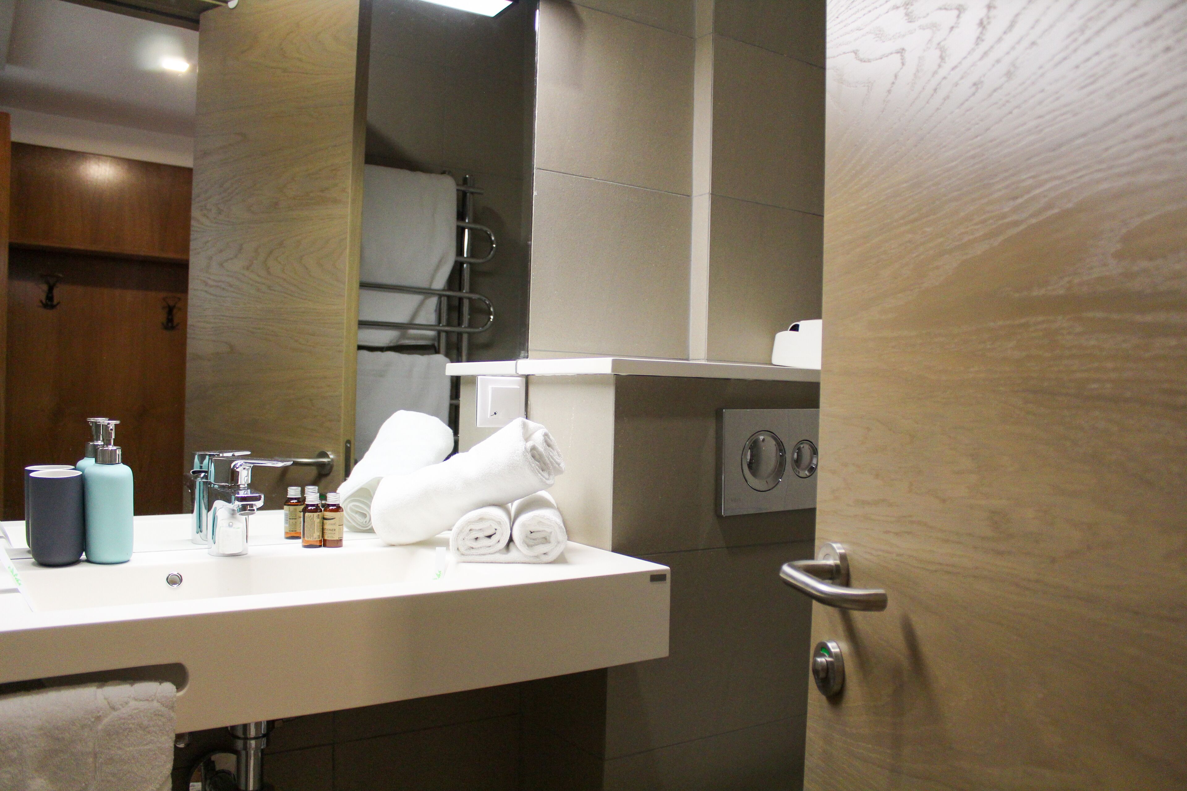 A bathroom with a white sink, two bottles, and towels.