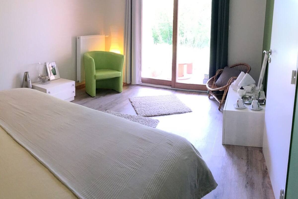Een slaapkamer met een bed, een stoel, een lamp en uitzicht op het landschap.